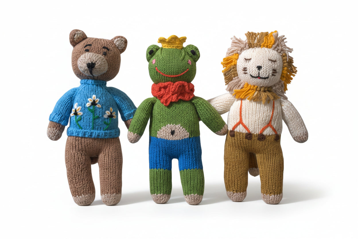 Three knitted toys: a bear, frog, and lion, wearing colorful outfits.